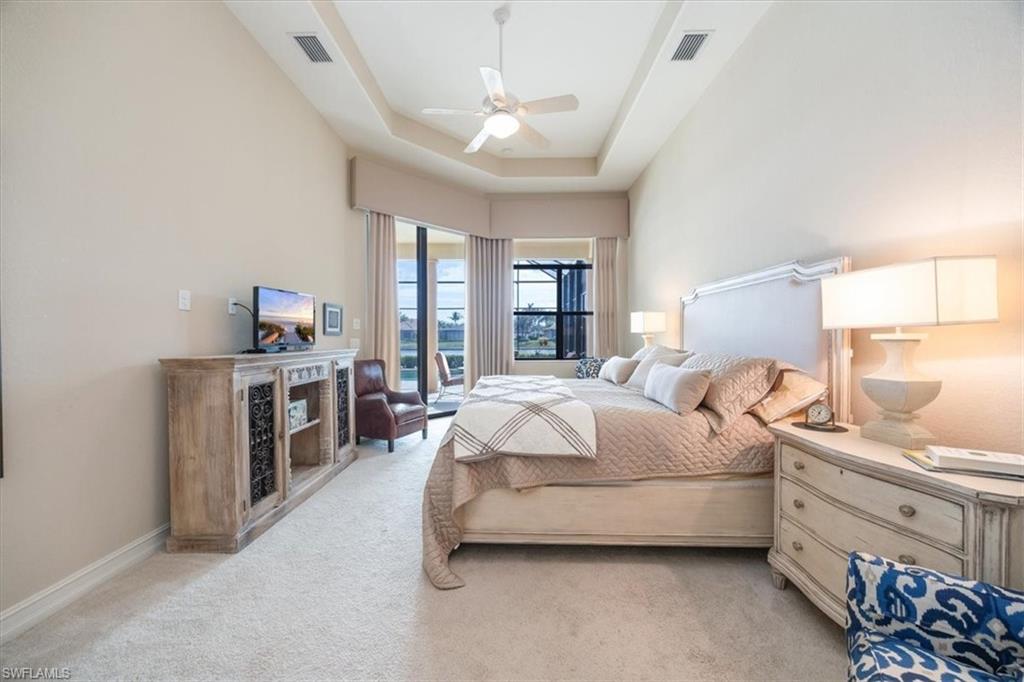 6504 Costa Circle Naples, FL 34113 - Photo 11 of 25 Bedroom with a tray ceiling, visible vents, a ceiling fan, and light carpet