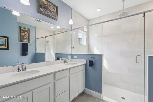 a bathroom with a double vanity sink mirror and shower