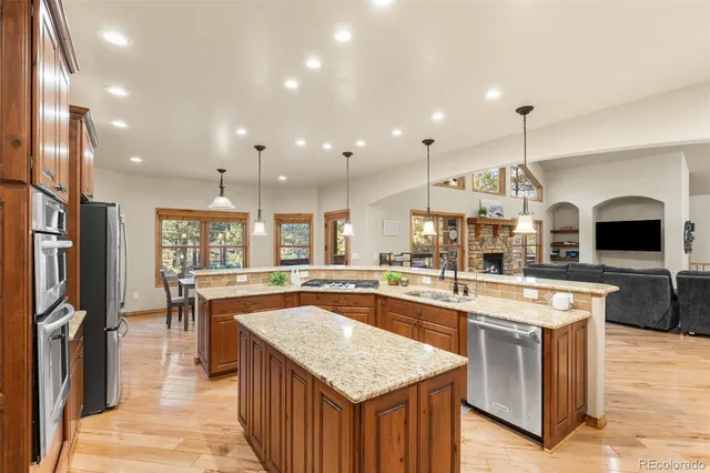 a kitchen with stainless steel appliances granite countertop a kitchen island a stove and a sink