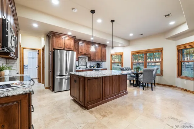 a kitchen with stainless steel appliances granite countertop a table chairs refrigerator and sink