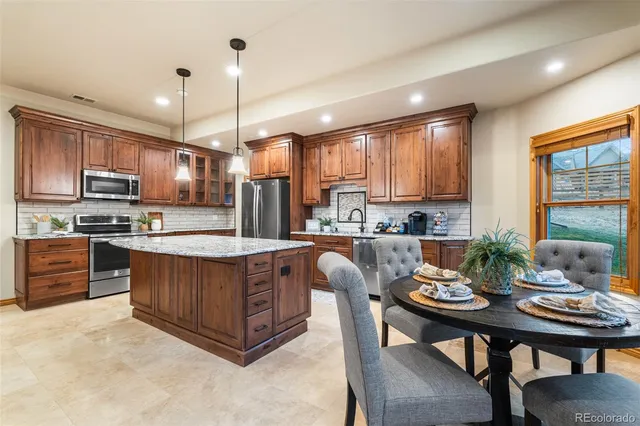 a kitchen with granite countertop a table chairs microwave and cabinets