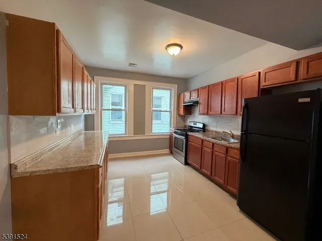a kitchen with granite countertop stainless steel appliances and refrigerator