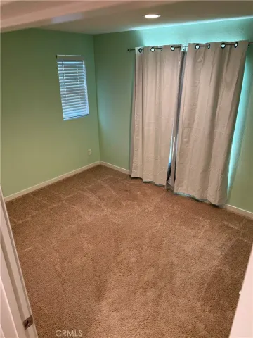 a view of an empty room with closet and a window