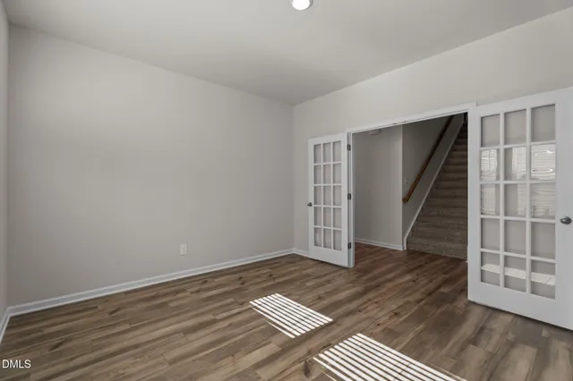 a view of an empty room with wooden floor and stairs