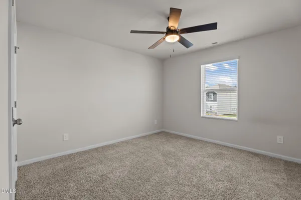 an empty room with a window and a fan