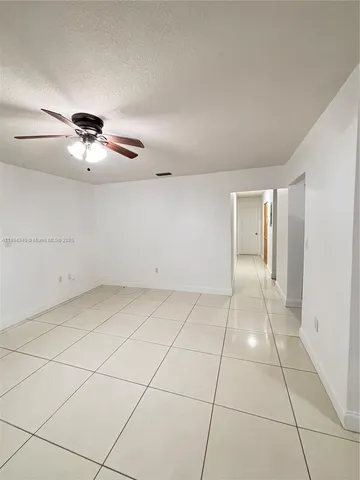 a view of an empty room and chandelier fan