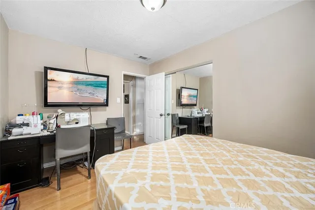 a bedroom with a large bed and a flat tv screen on dresser