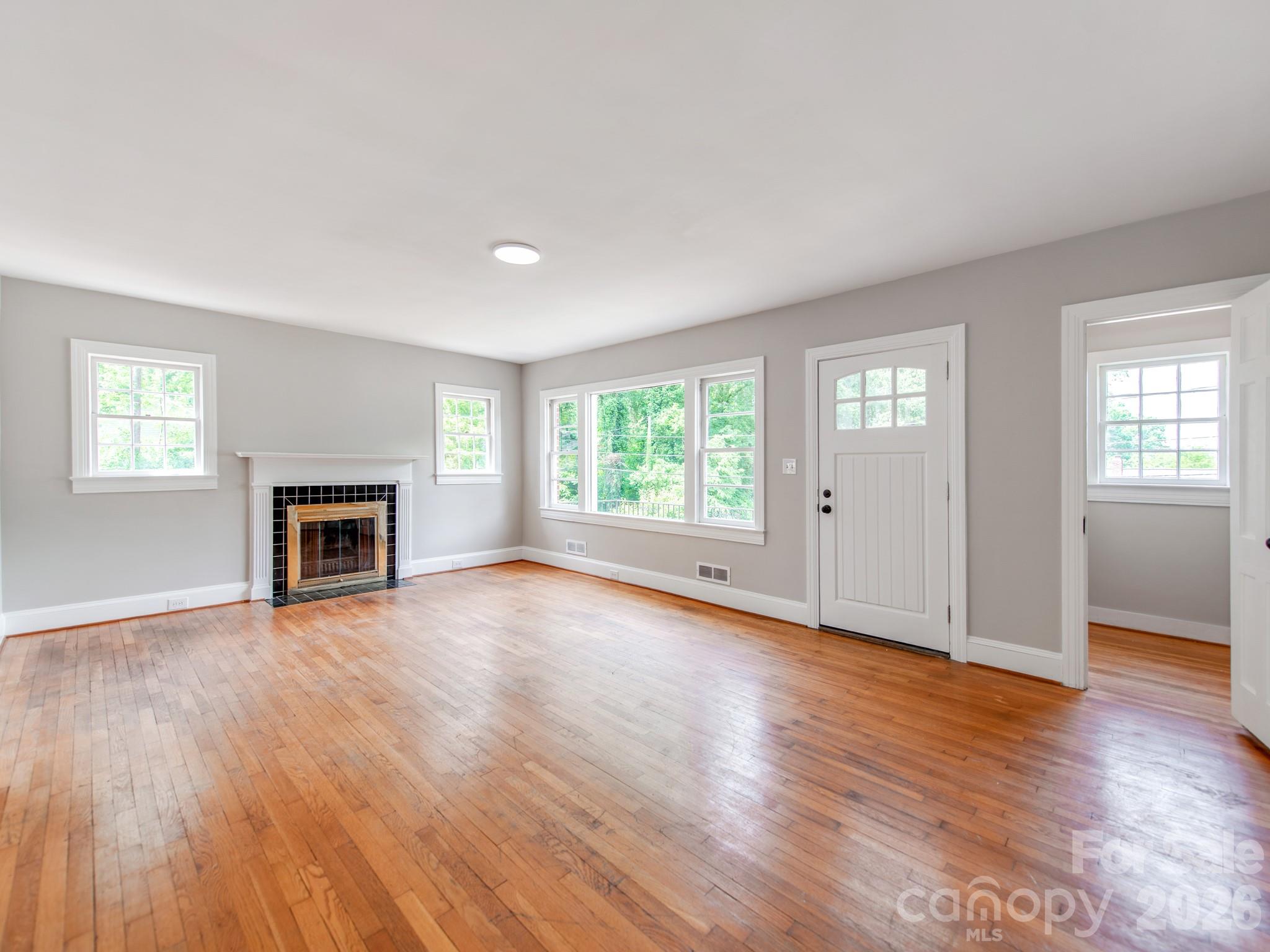 113 Falls Street Morganton, NC 28655 - Photo 5 of 33 an empty room with wooden floor fireplace and windows