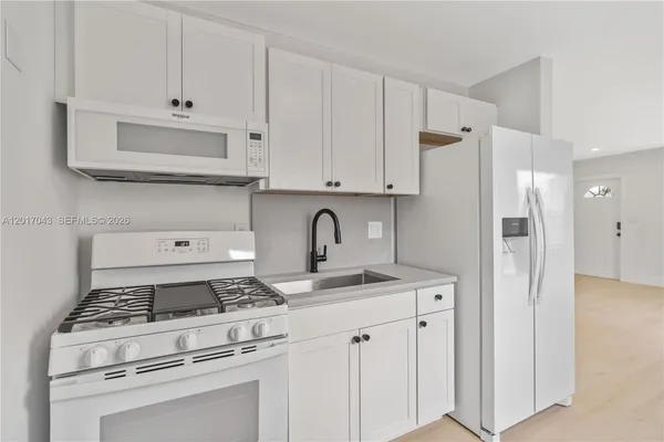 a kitchen with stainless steel appliances granite countertop a stove a refrigerator and a white cabinets