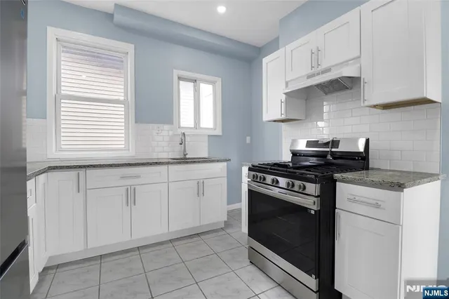 a kitchen with granite countertop white cabinets and appliances