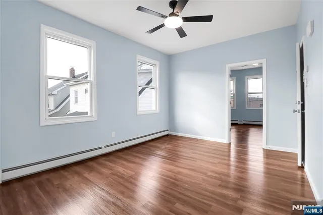 a view of empty room with wooden floor and fan