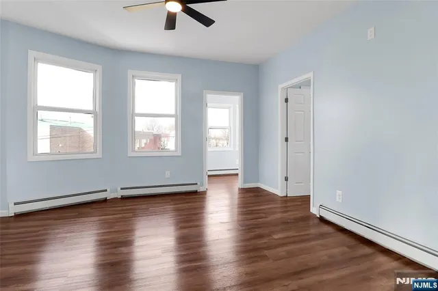 a view of an empty room with window and wooden floor