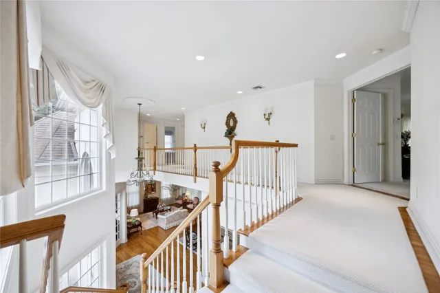 a view of a hallway to a livingroom with wooden floor and windows