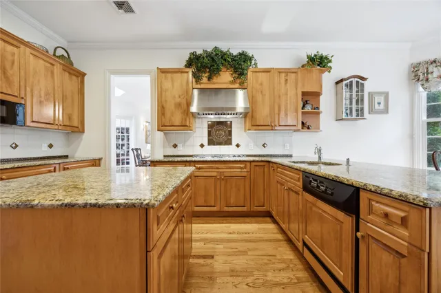 a kitchen with kitchen island granite countertop a sink stove and cabinets