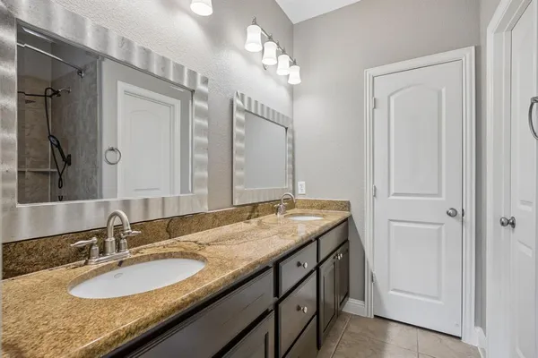 a bathroom with a granite countertop sink double vanity and a mirror
