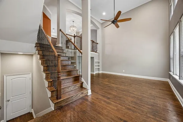 an empty room with wooden floor staircase and windows