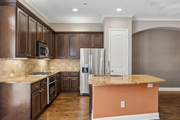 a kitchen with granite countertop wood cabinets stainless steel appliances and a sink