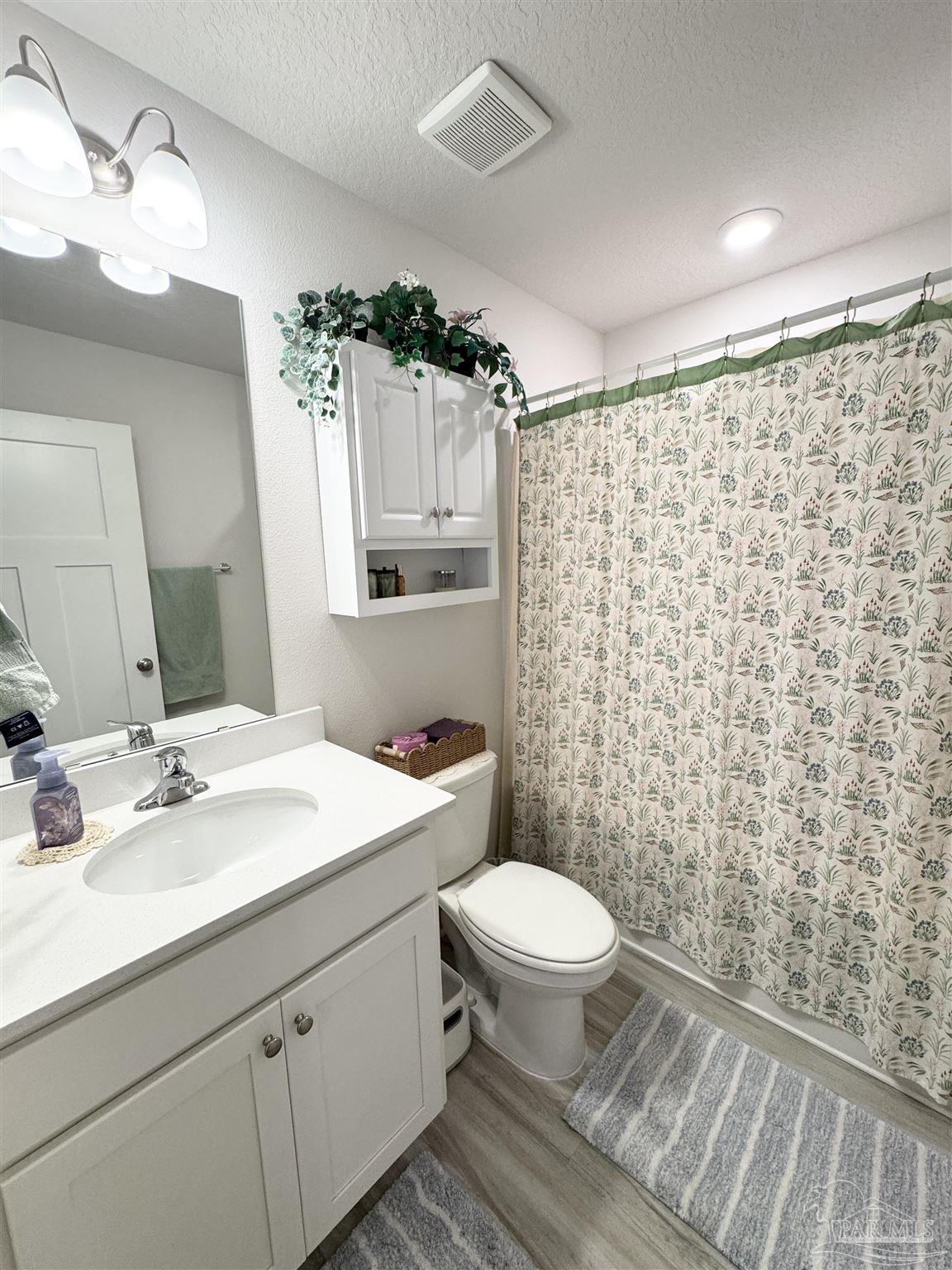3315 Garganey Road Pace, FL 32571 - Photo 16 of 52 a bathroom with a sink a toilet a mirror and shower curtain