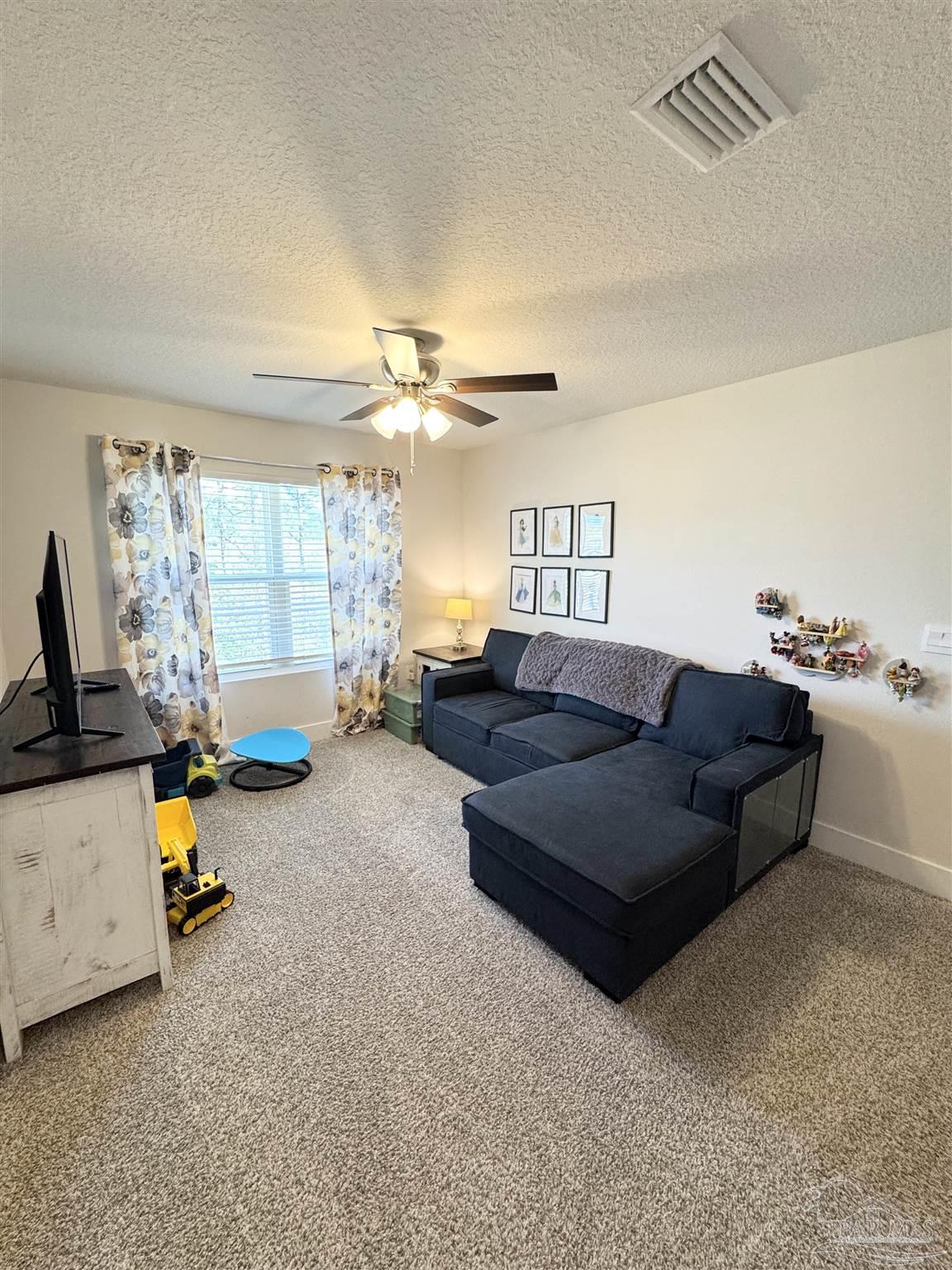 3315 Garganey Road Pace, FL 32571 - Photo 27 of 52 a living room with furniture a chandelier and a flat screen tv