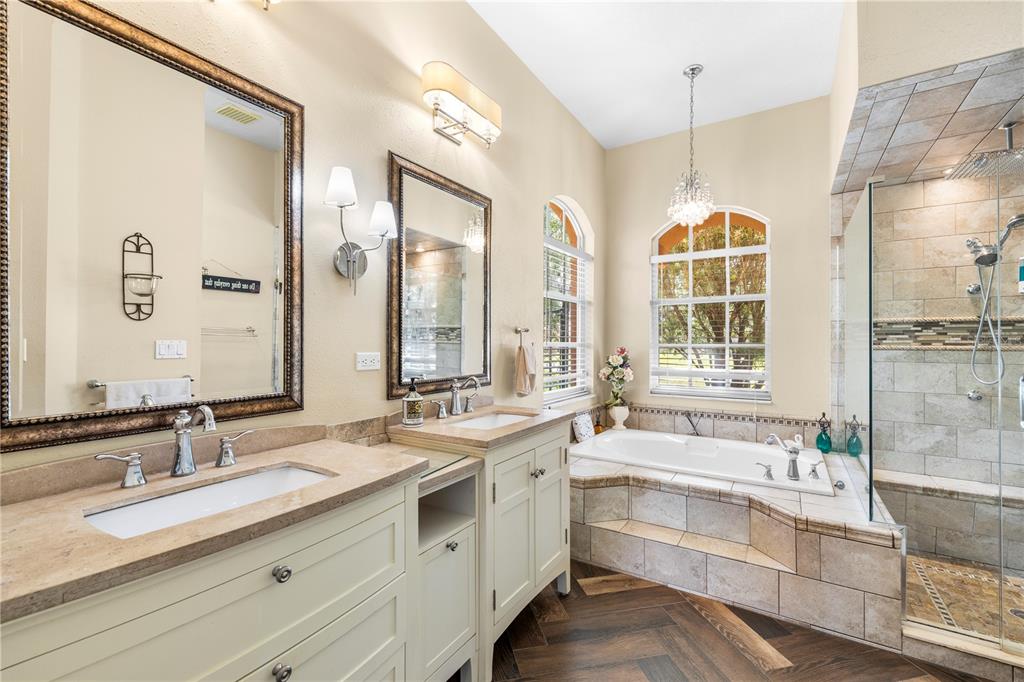 3051 Waterfall Drive Spring Hill, FL 34608 - Photo 22 of 74 a bathroom with double vanity sinks a large mirror and a bathtub next to a window