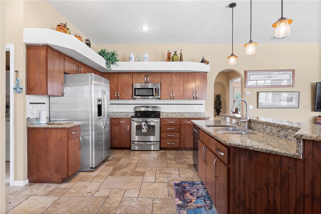 3051 Waterfall Drive Spring Hill, FL 34608 - Photo 3 of 74 a kitchen with stainless steel appliances granite countertop a sink a stove and a refrigerator