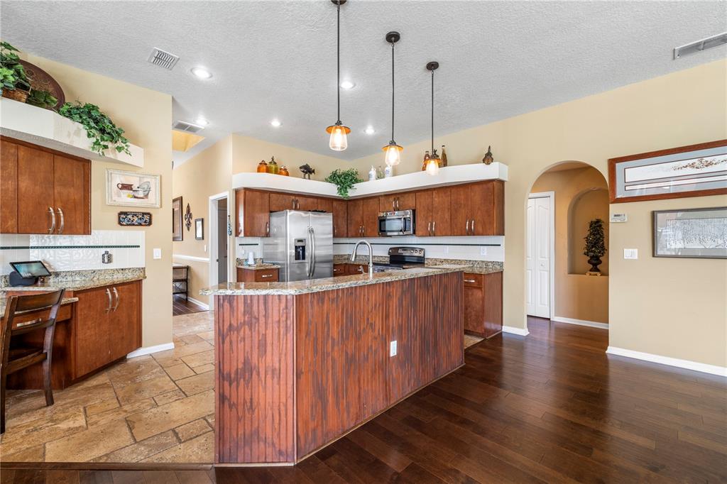 3051 Waterfall Drive Spring Hill, FL 34608 - Photo 62 of 74 a large kitchen with stainless steel appliances granite countertop a stove a sink dishwasher a refrigerator white cabinets and wooden floor