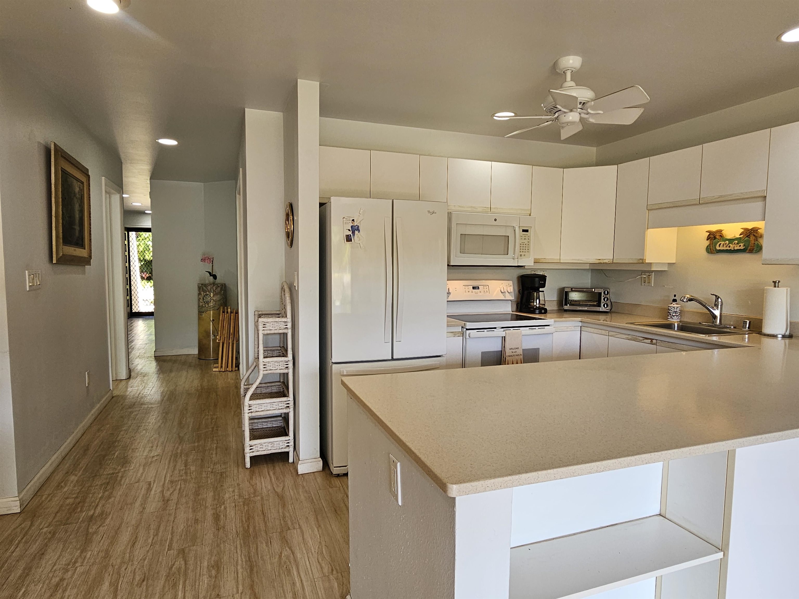 2777 South Kihei Road, Unit K107 Kihei, HI 96753 - Photo 19 of 50 a kitchen with stainless steel appliances granite countertop a refrigerator a stove and a sink with wooden floor