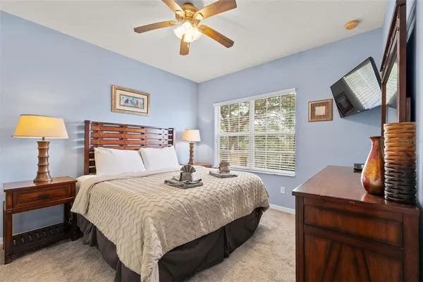 a bedroom with a bed and a lamp on dresser next to a window