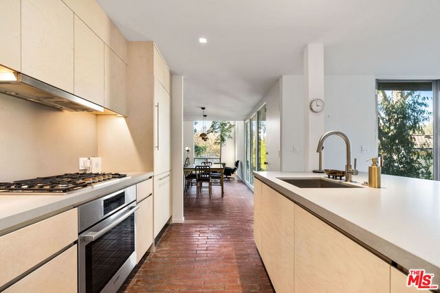 a kitchen with sink a stove and chairs with wooden floor