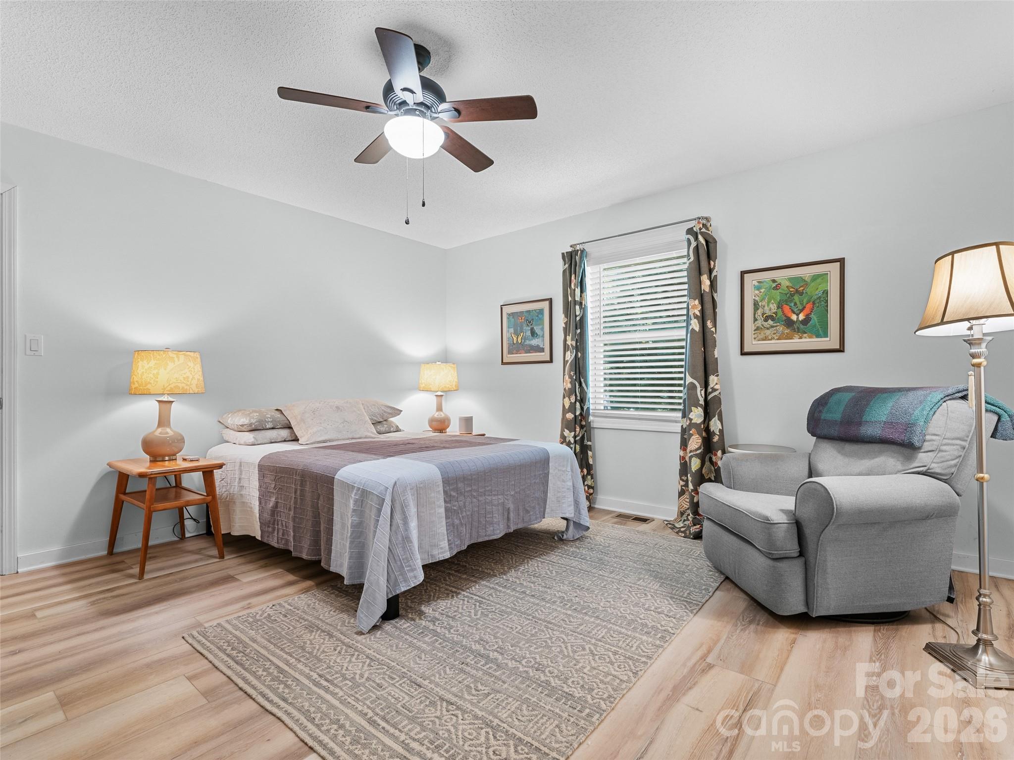 1756 Happy Acres Road Brevard, NC 28712 - Photo 26 of 35 a spacious bedroom with a bed a couch and a chandelier