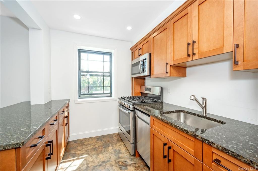 a kitchen with granite countertop a sink a stove cabinets counter top space and stainless steel appliances
