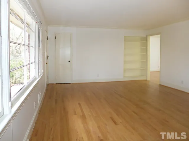 a view of an empty room with wooden floor and a window