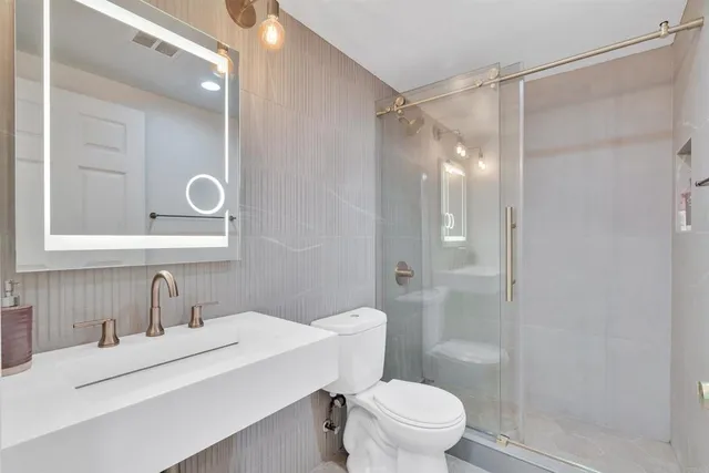 a bathroom with a sink toilet vanity and shower