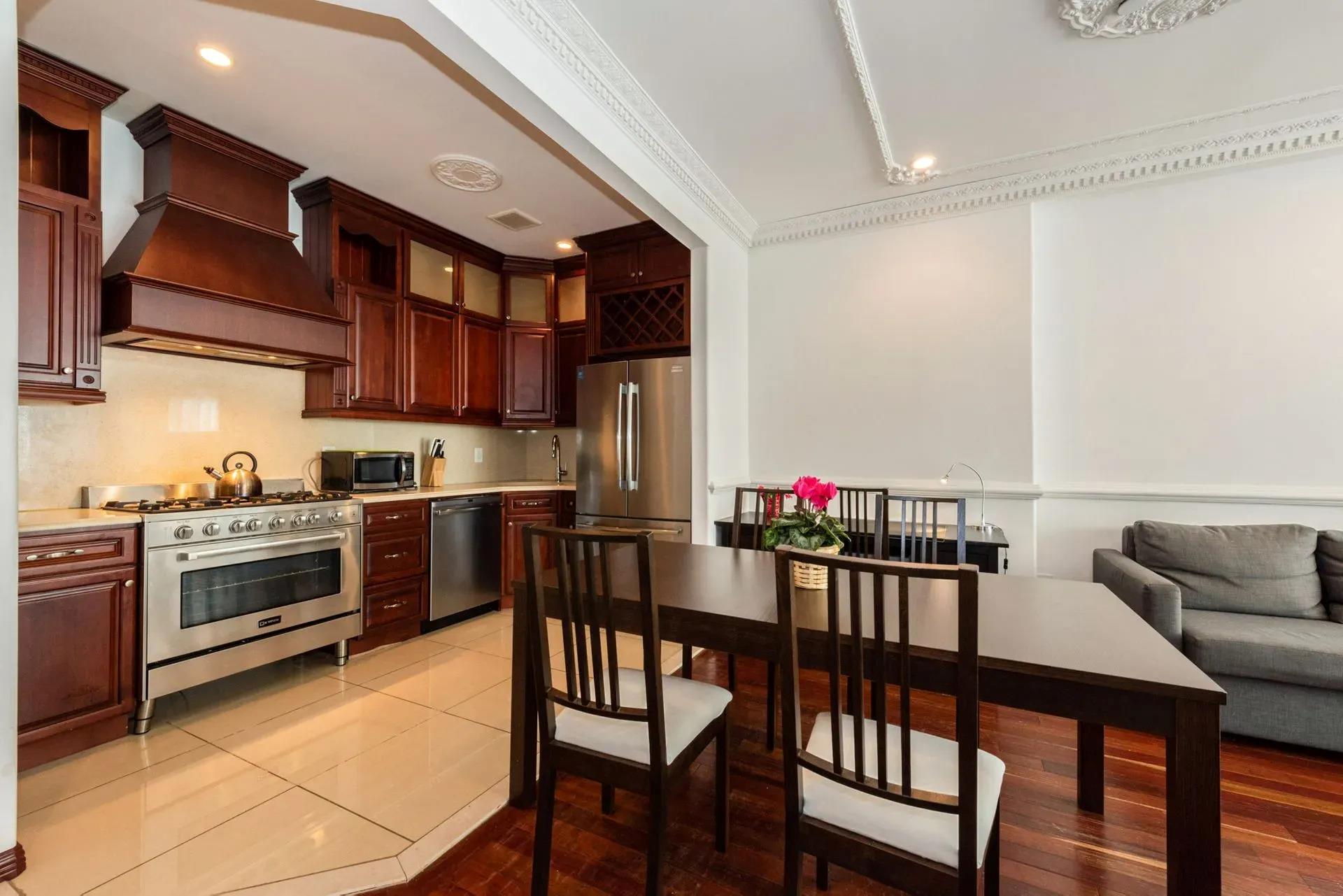 475 West 146th Street Manhattan, NY 10031 - Photo 5 of 19 a kitchen with stainless steel appliances granite countertop a stove top oven a dining table and chairs with wooden floor