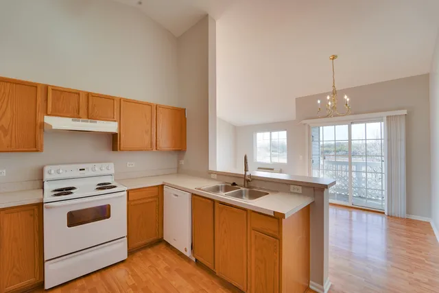 a kitchen that has a sink a stove top oven and wooden floor