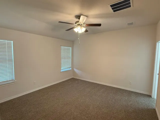 an empty room with wooden floor fan and window