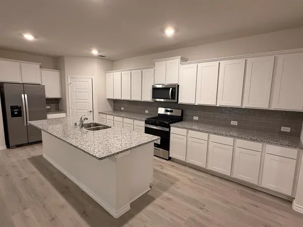 a kitchen with kitchen island granite countertop a sink appliances cabinets and counter space