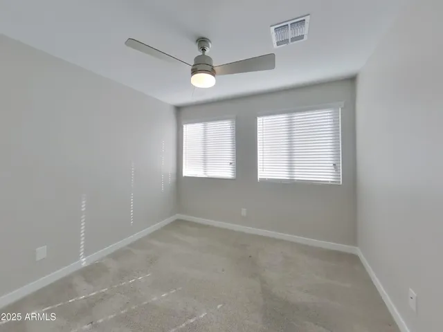 an empty room with a window and a ceiling fan