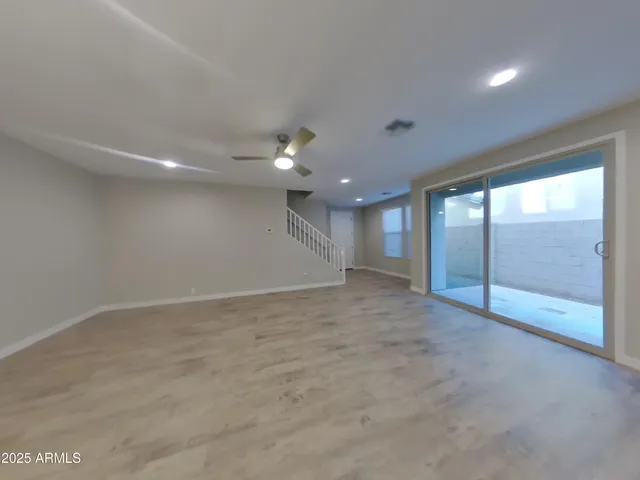 a view of an empty room with kitchen and window