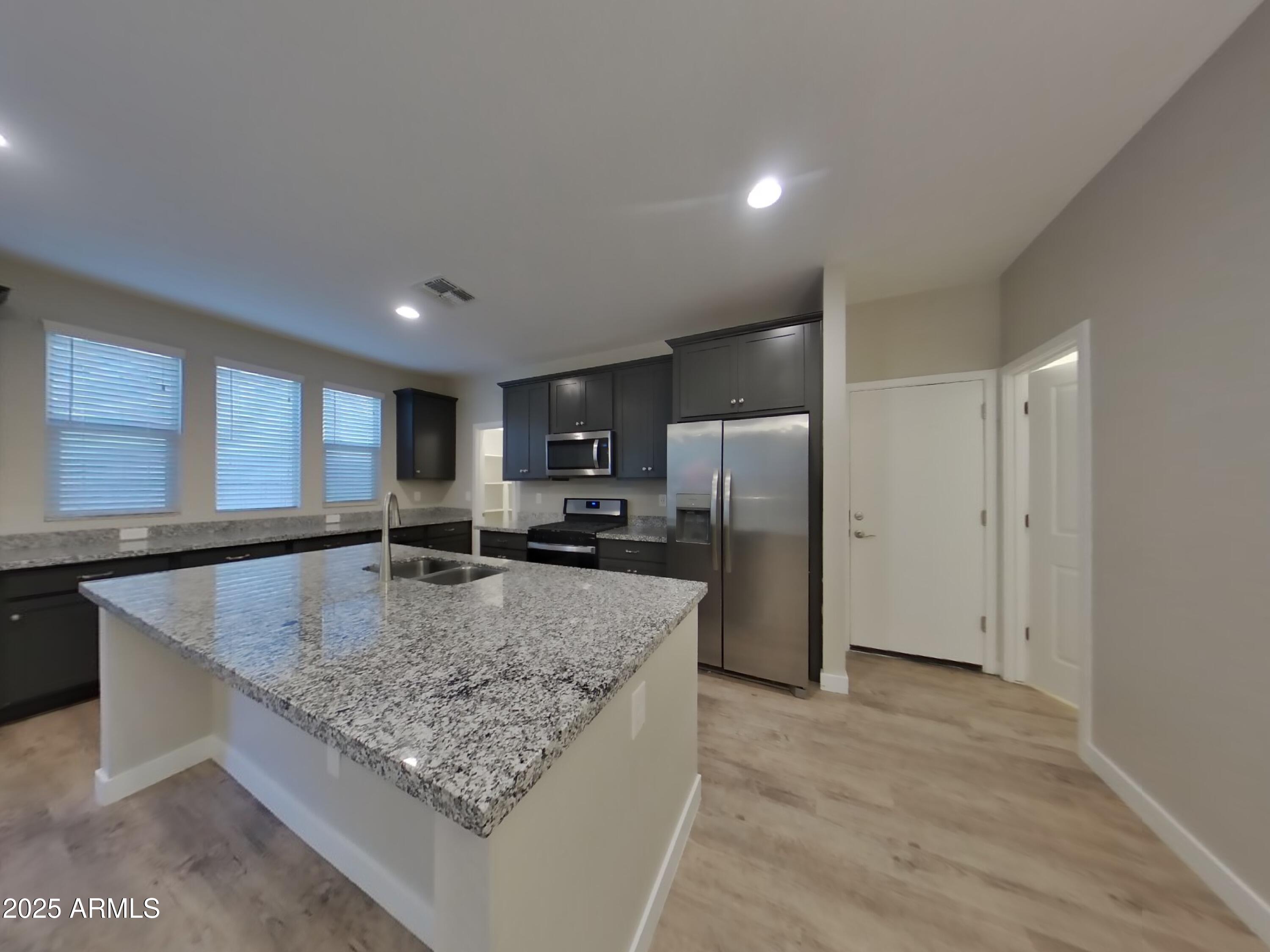 9314 East Strobe Avenue Mesa, AZ 85212 - Photo 6 of 27 a kitchen with stainless steel appliances granite countertop a sink a refrigerator and a granite counter tops