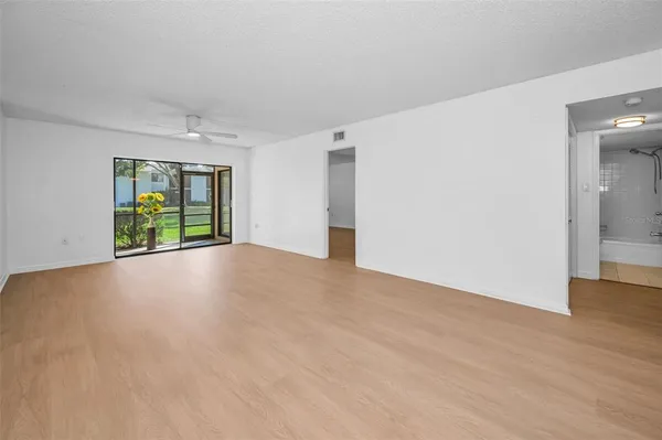 a view of an empty room with wooden floor and a window