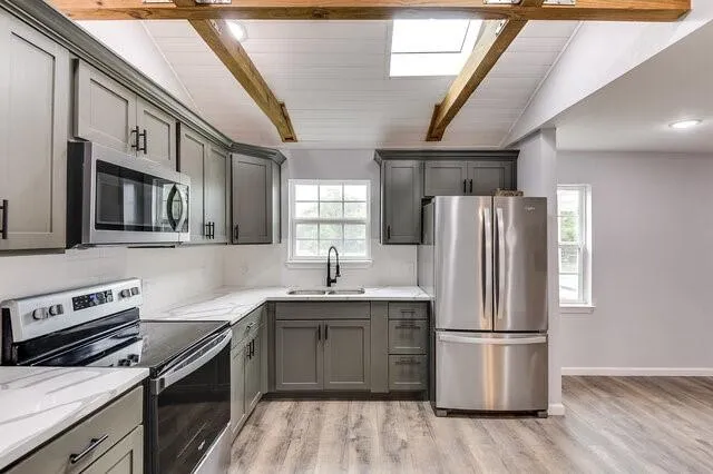 a kitchen with stainless steel appliances a refrigerator a sink a stove a microwave and wooden floors