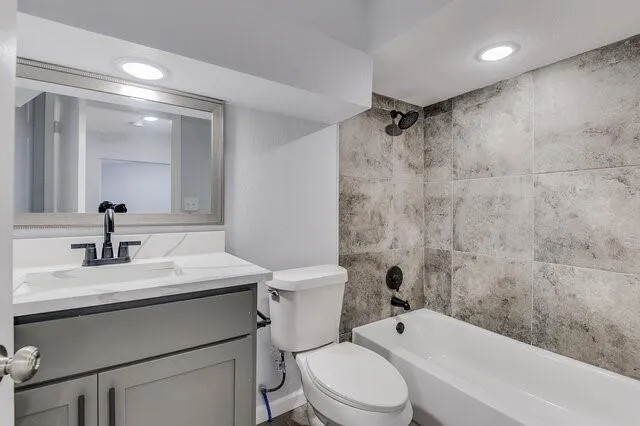 a bathroom with a toilet a sink a mirror a bathtub and vanity