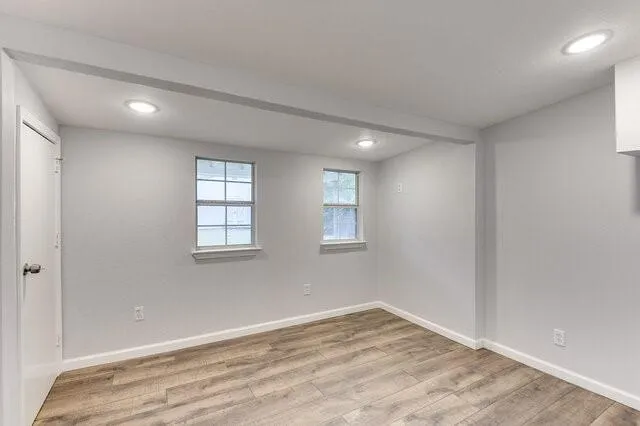 a view of empty room with wooden floor and fan