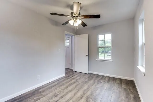 a view of empty room with wooden floor and fan