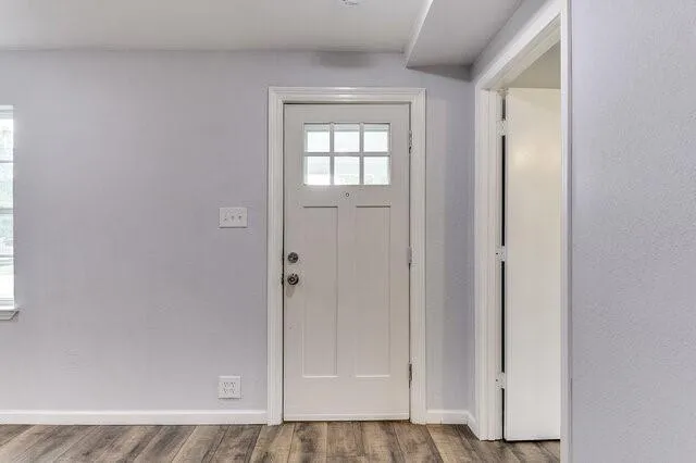 an empty room with wooden floor closet and windows