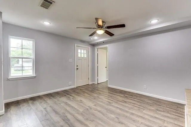 a view of empty room with wooden floor and fan