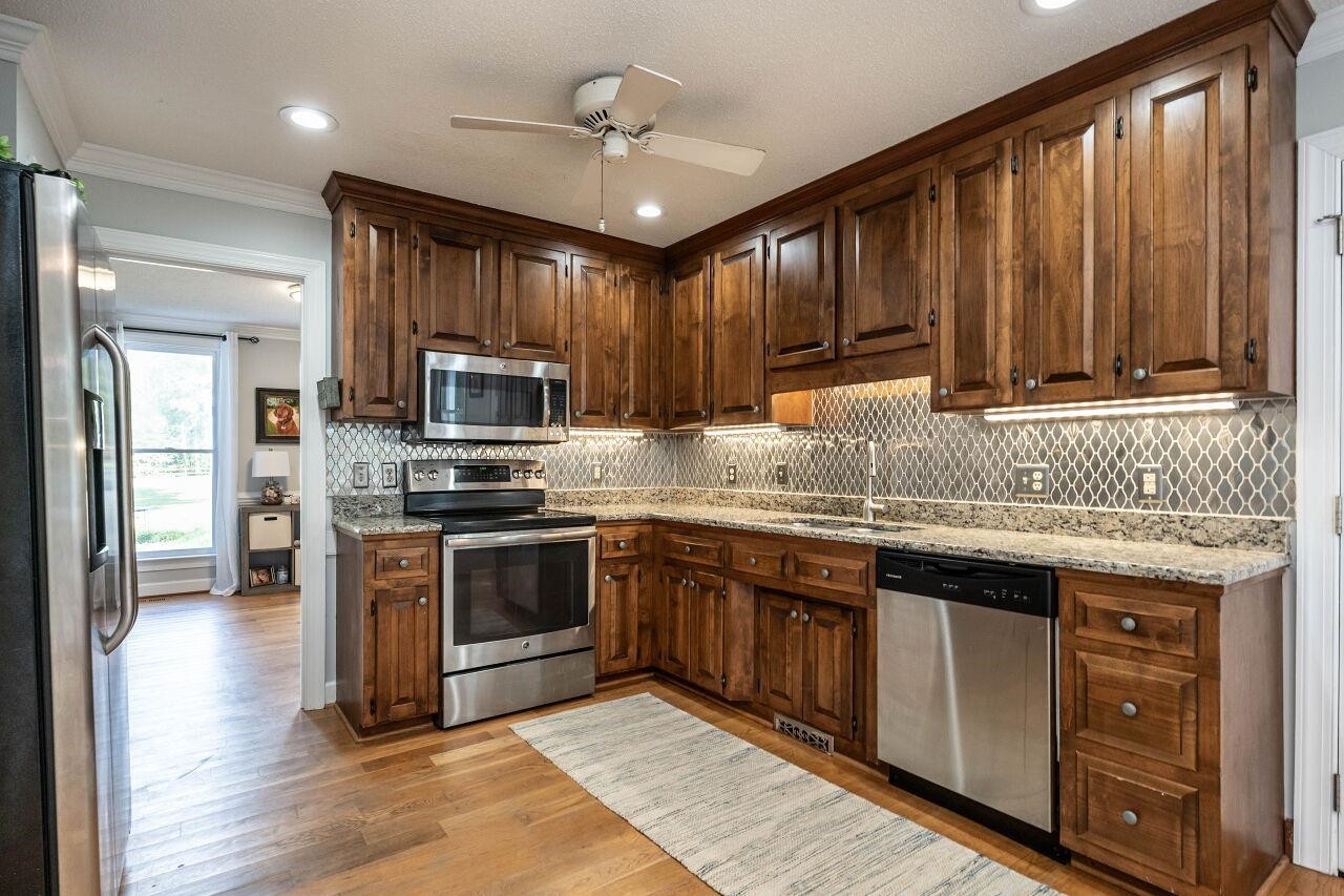 5924 Clearsprings Drive Wake Forest, NC 27587 - Photo 13 of 37 a kitchen with granite countertop wooden cabinets a sink stainless steel appliances and a window