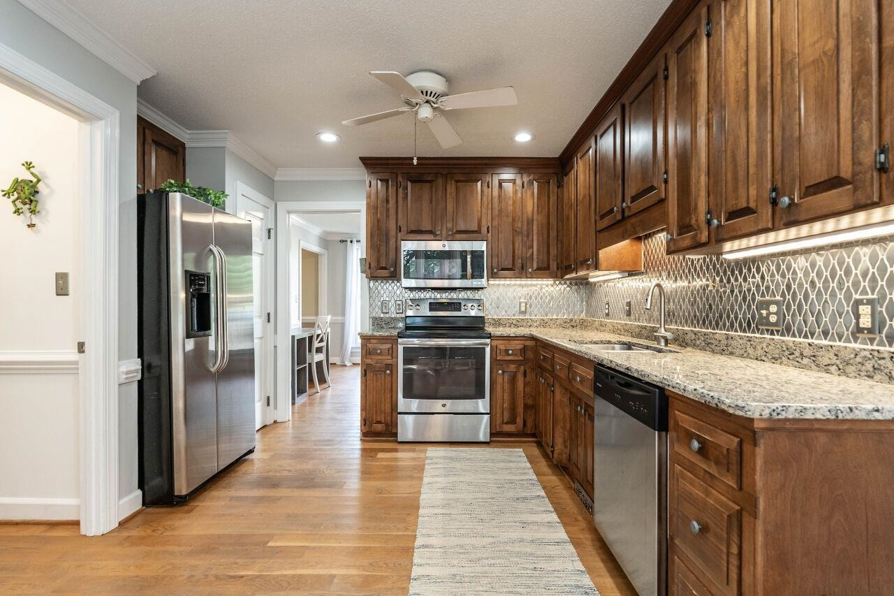 5924 Clearsprings Drive Wake Forest, NC 27587 - Photo 14 of 37 a kitchen with stainless steel appliances granite countertop a stove top oven a sink and a refrigerator