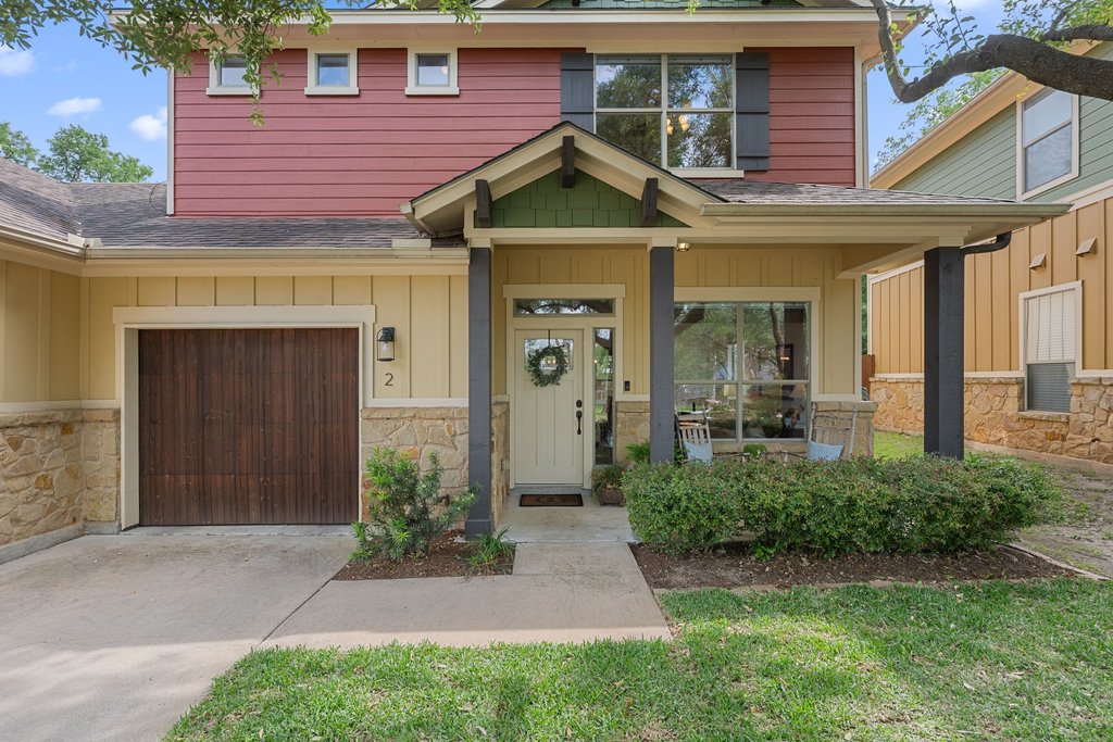6708 Menchaca Road, Unit 2 Austin, TX 78745 - Photo 1 of 30 Multi-level exterior featuring a covered porch, stone veneer siding, wood-finish garage door, and mature landscaping